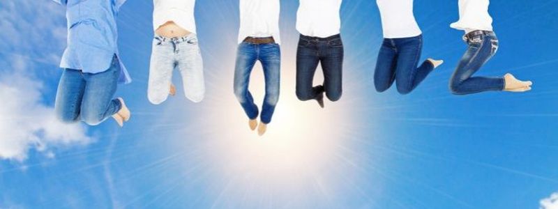 Der Himmel mit Sonne sowie sechs Menschen deren untere Körperhälfte man sieht, da sie hoch springen