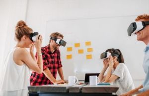 4 Menschen an einem Arbeitstisch mit VR-Brillen auf